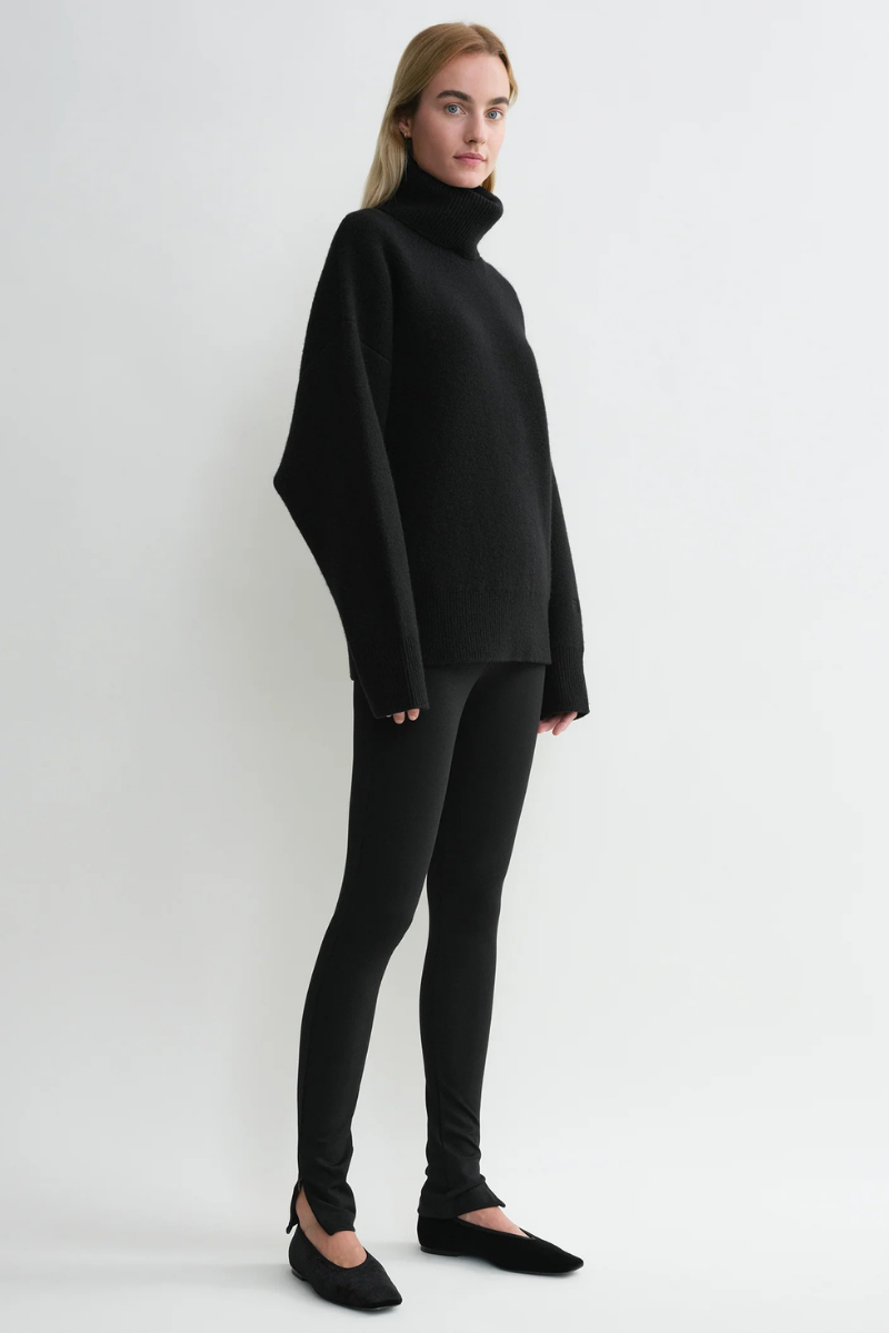 Model wearing Toteme Zip Leggings in Black with a stylish black turtleneck sweater.