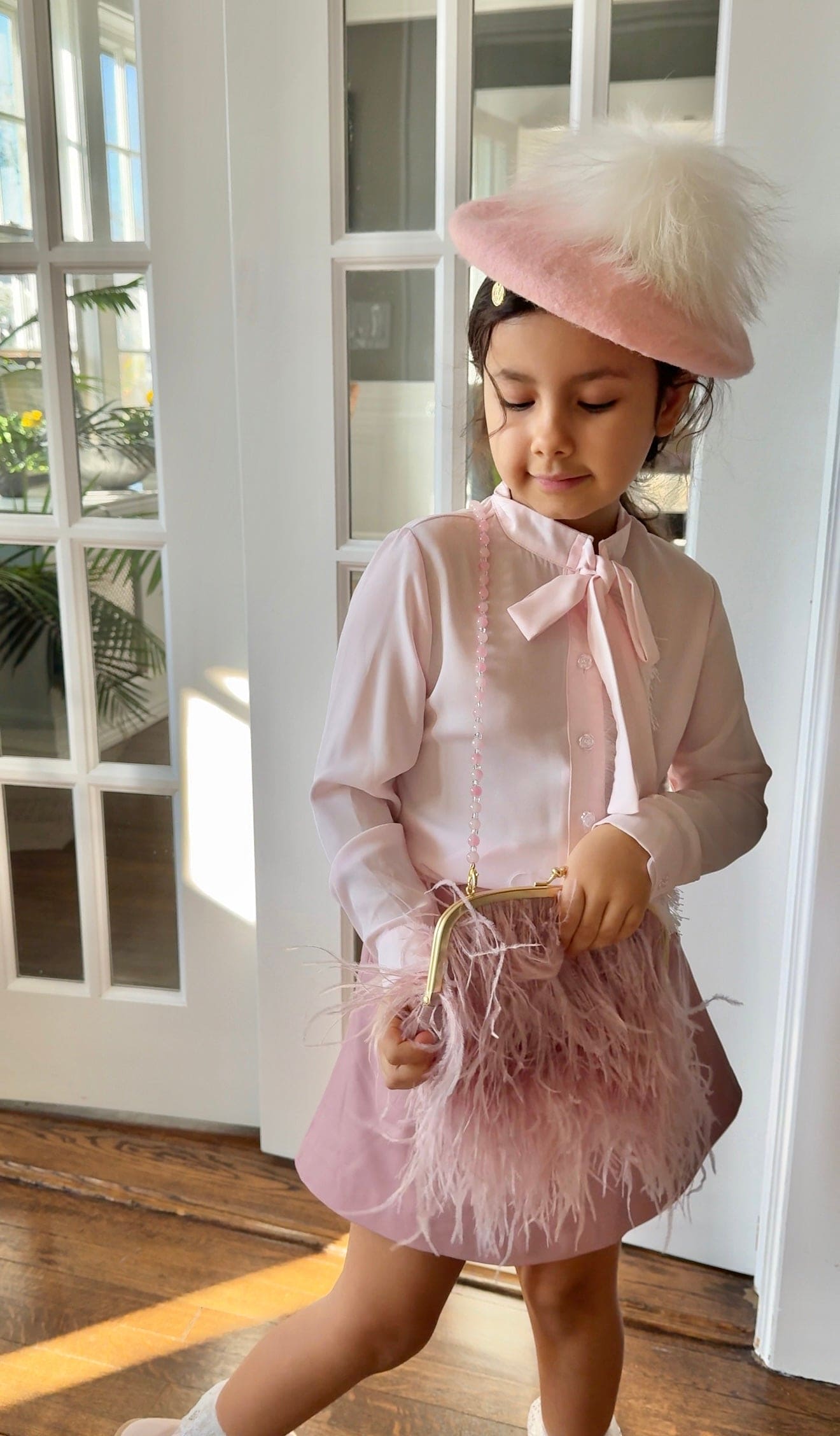 Blush pink girls outfit with bow blouse, matching skirt, feather purse, and pink beret