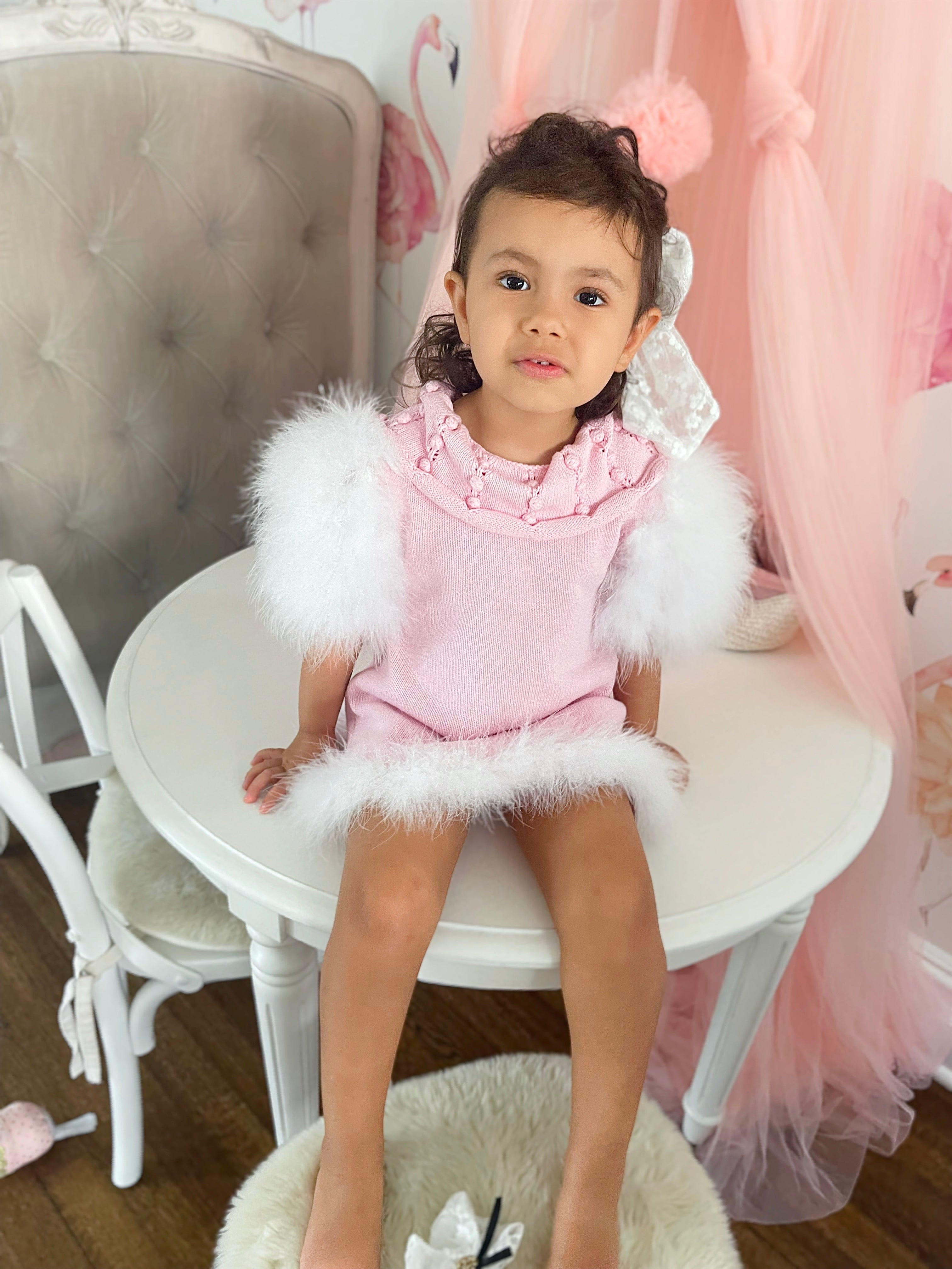 Girl wearing Ella Knit pink feather dress with fluffy sleeves and embellished collar
