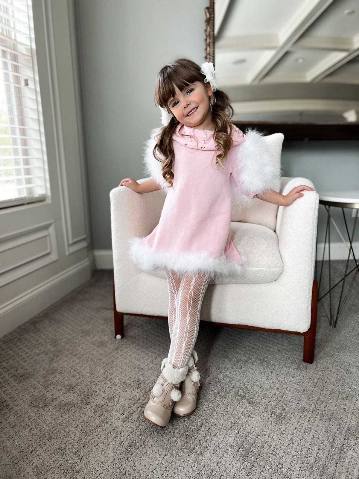 Young girl modeling Ella Knit Pink Feather Dress with decorative collar detail and puff sleeves and matching fur trim