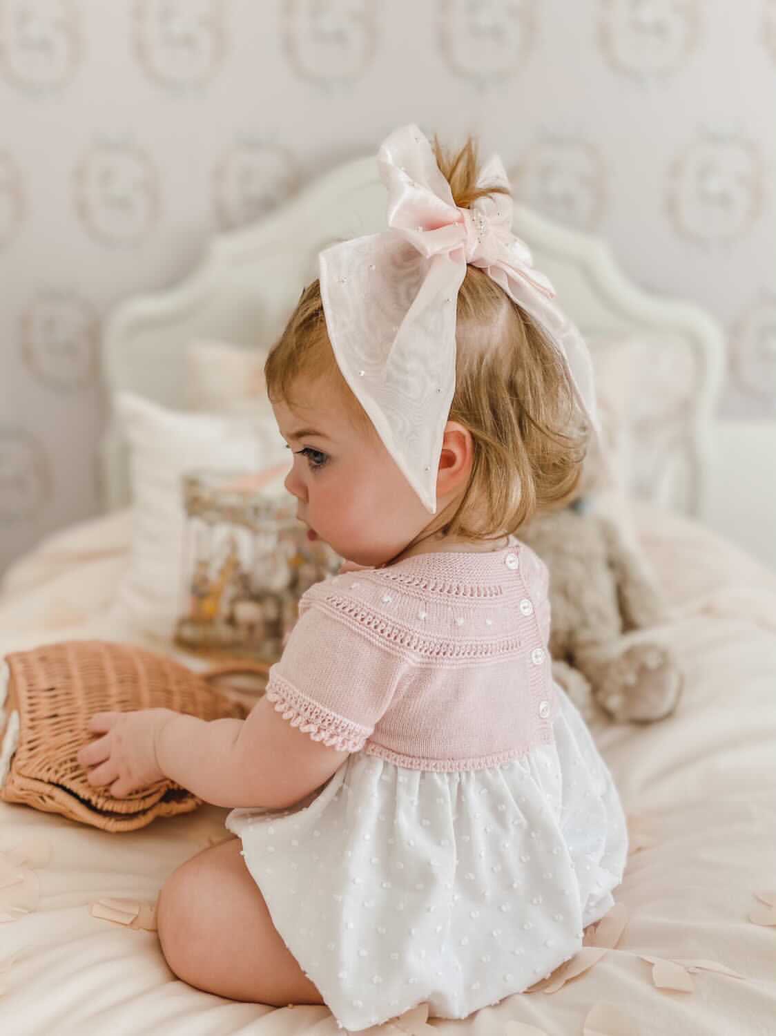 Baby in blush outfit wearing the Juliette Pink Organza Hair Bow with delicate pearl detailing and statement oversized bow.