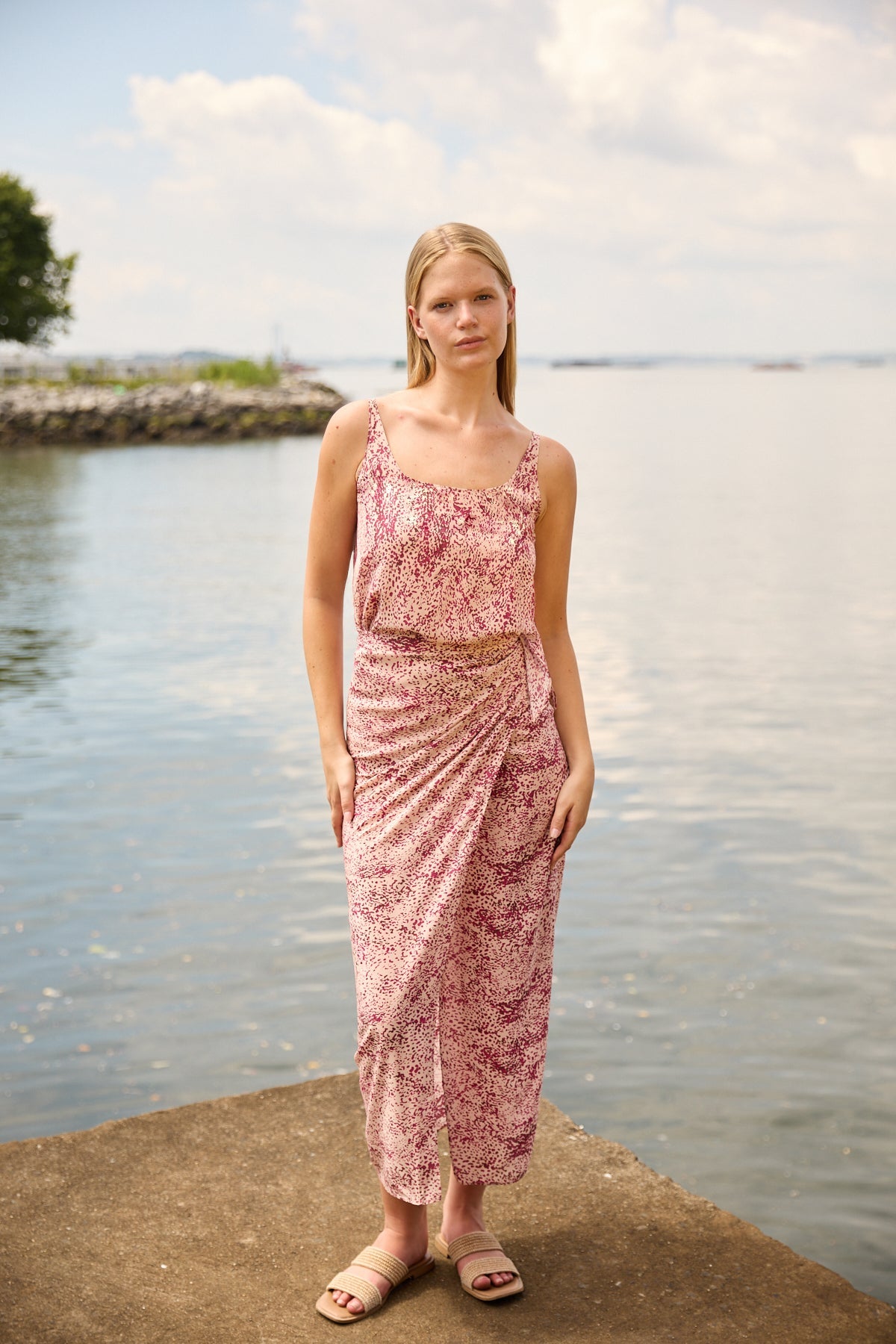 Du & Berry convertible silk wrap dress in pink floral pattern worn by model near water