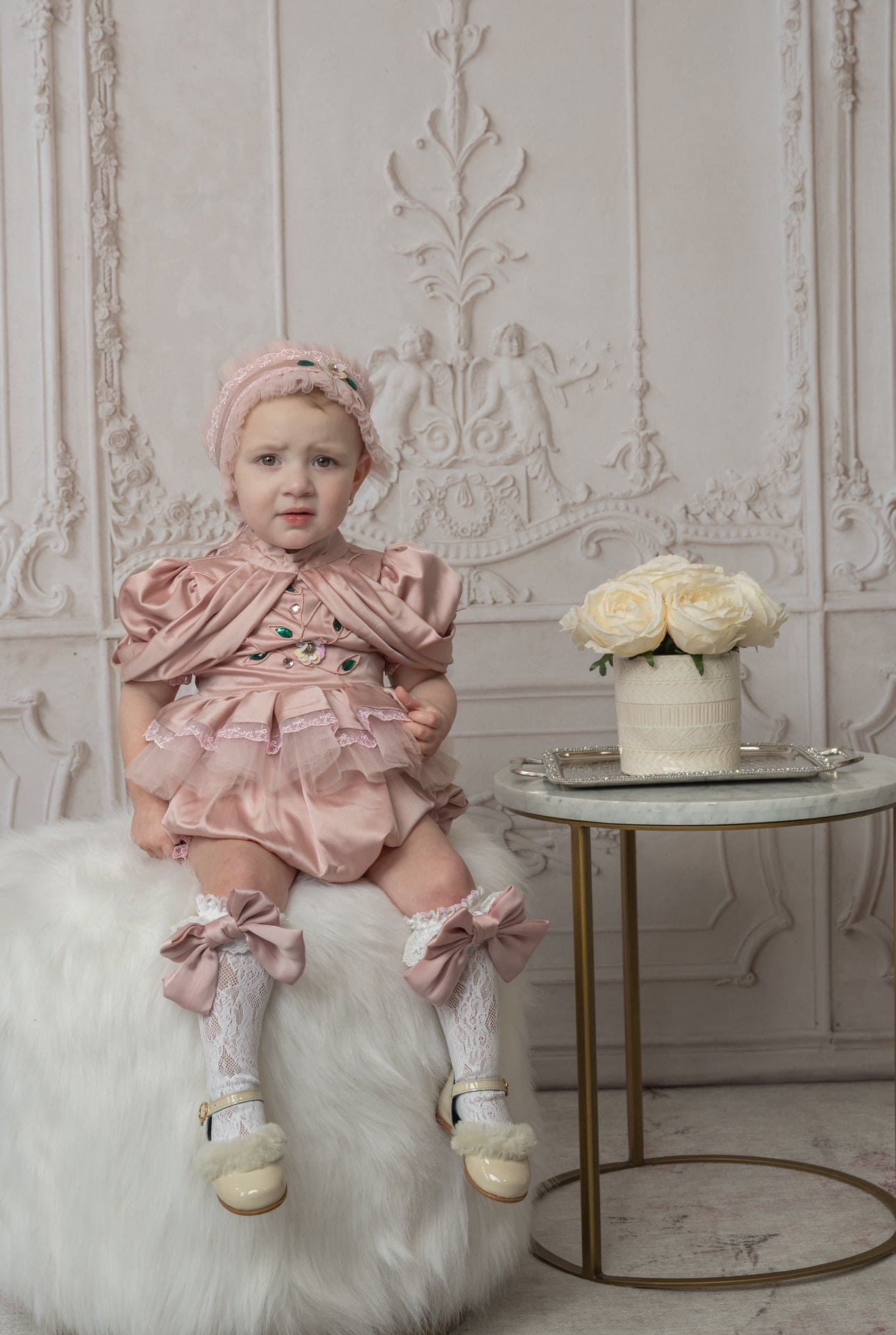 Pink satin ballerina romper with delicate tulle lace, emerald embellishments, and draped sleeves, designed for special occasions and photo shoots.