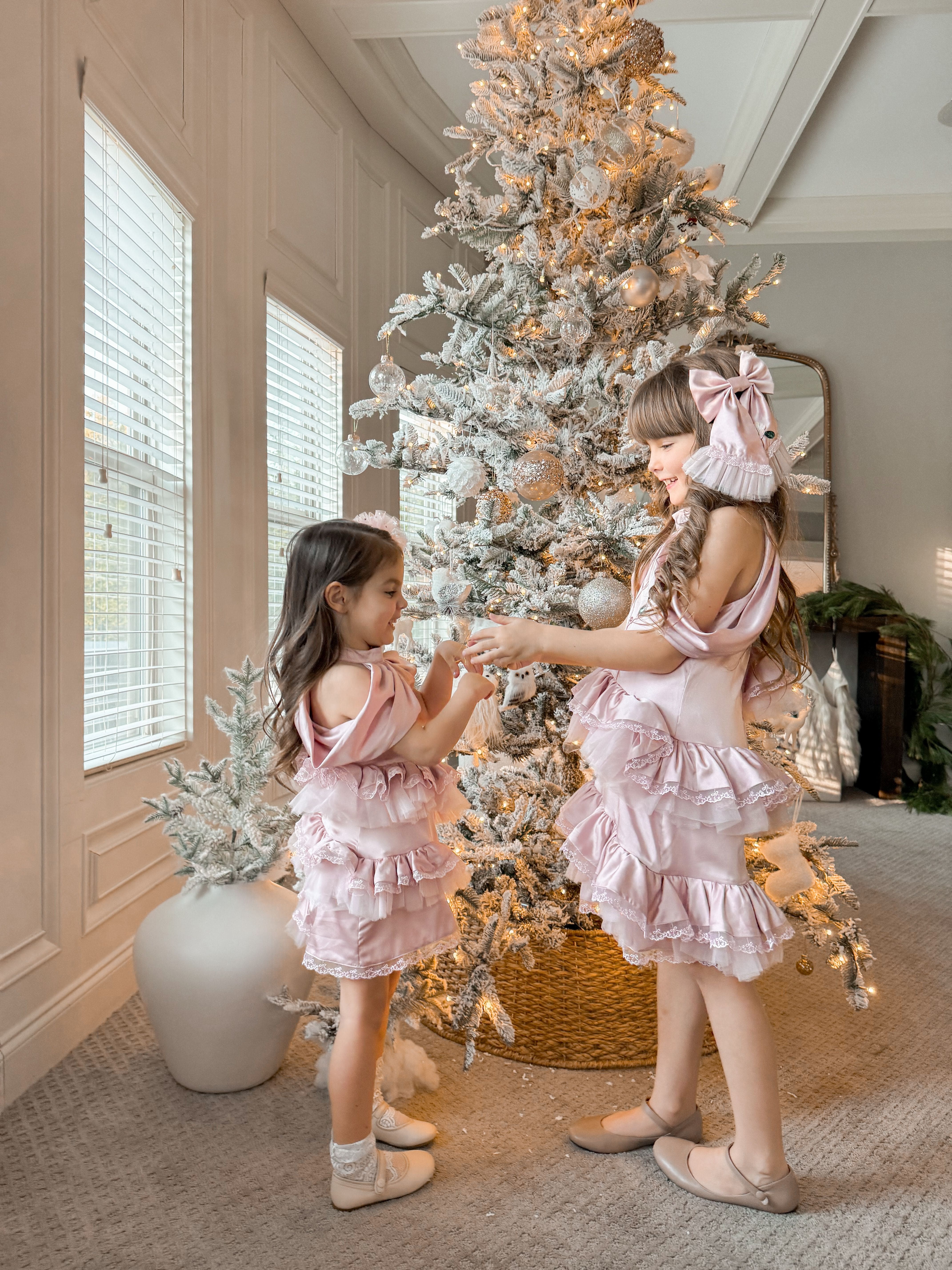 Side view of pink satin ballerina dress highlighting off the shoulder satin drape and voluminous tutu style skirt