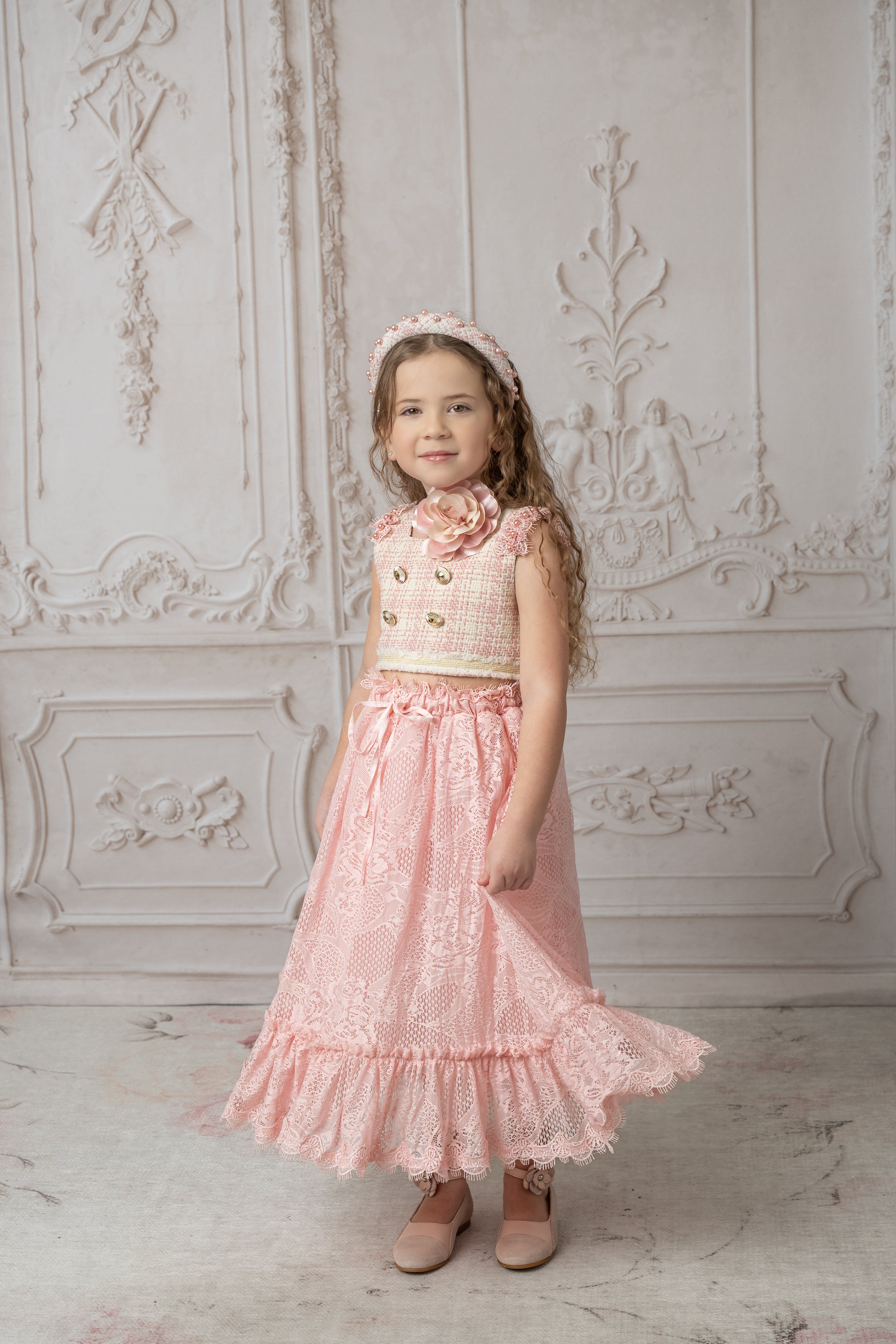 Girl with pink and beige tweed top with gold button details paired with a pink lace and ruffle skirt