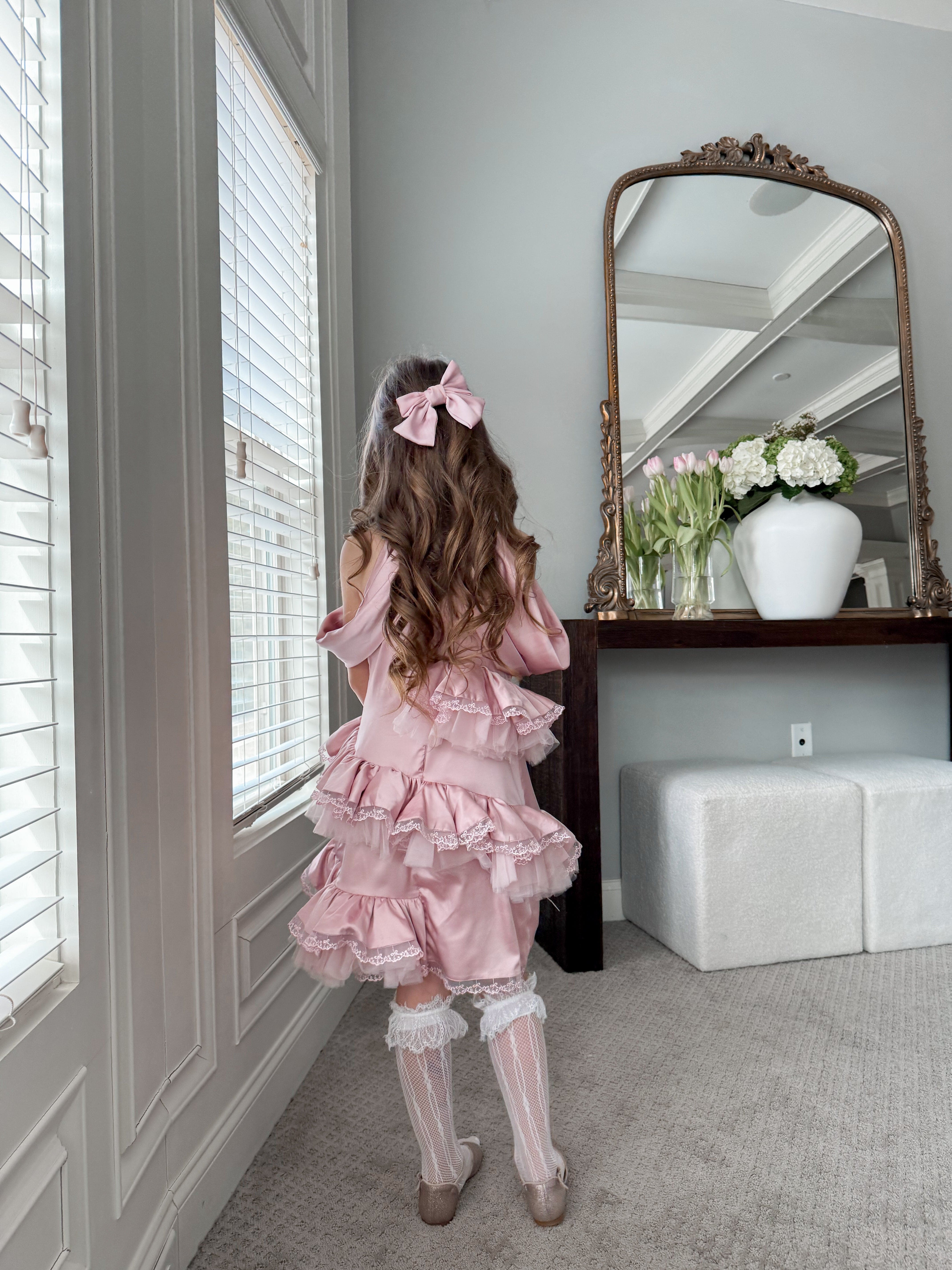 Back view of pink satin ballerina dress featuring cascading ruffled skirt, satin bow detail, and elegant ballet inspired silhouette