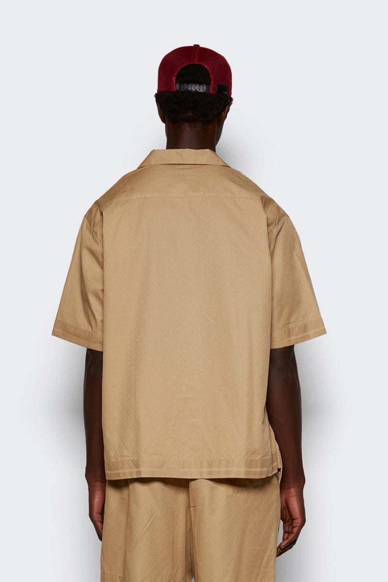 Back view of model wearing Givenchy Bowling Shirt Beige with a cap, showcasing its boxy fit and Hawaiian collar.