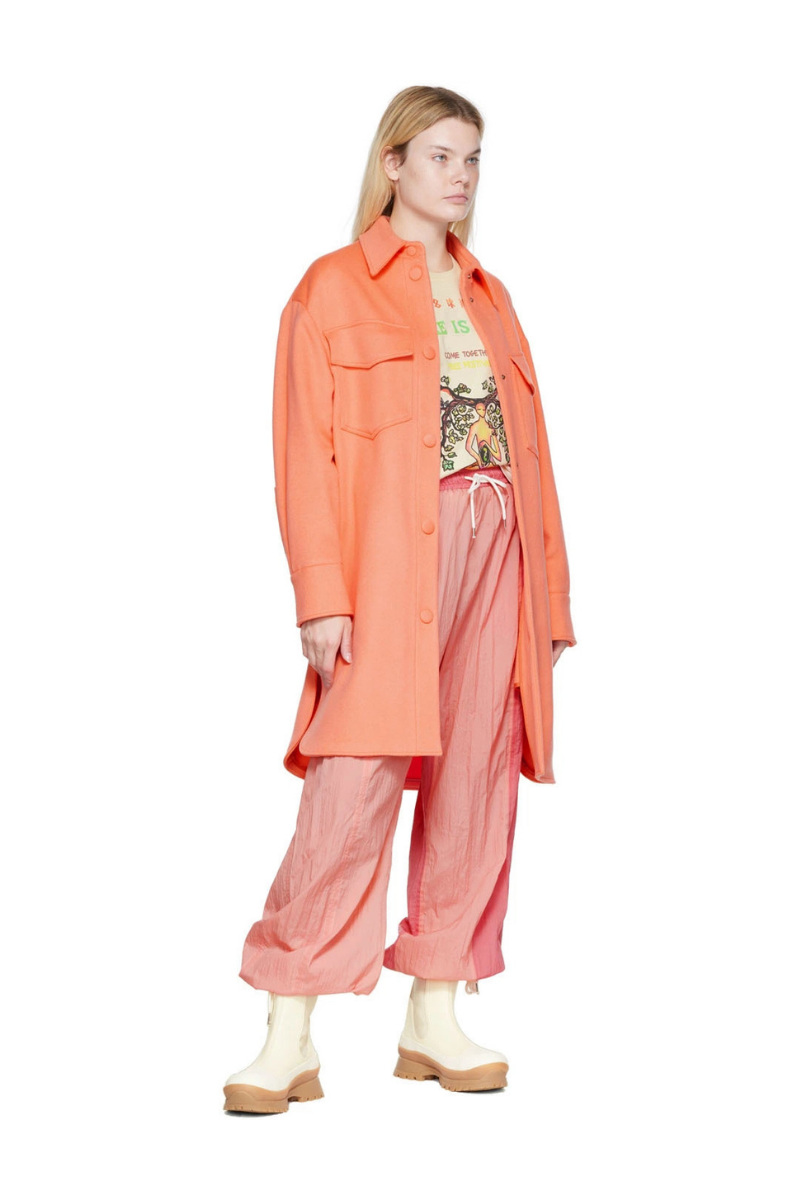 Stella McCartney Kerry Coat in Orange worn by a model with pink pants and cream boots.