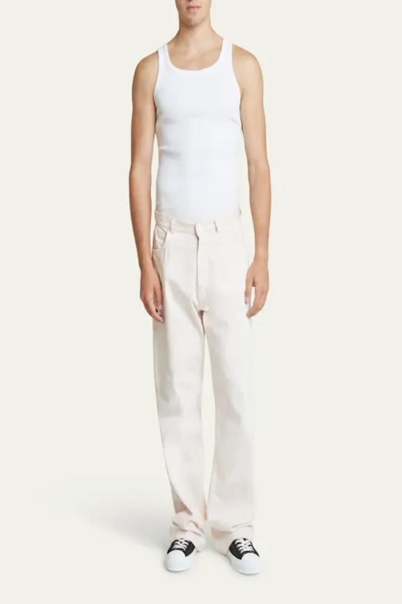 Givenchy Loose Straight-leg Jeans - Pale Pink modeled with a white tank top and black sneakers.