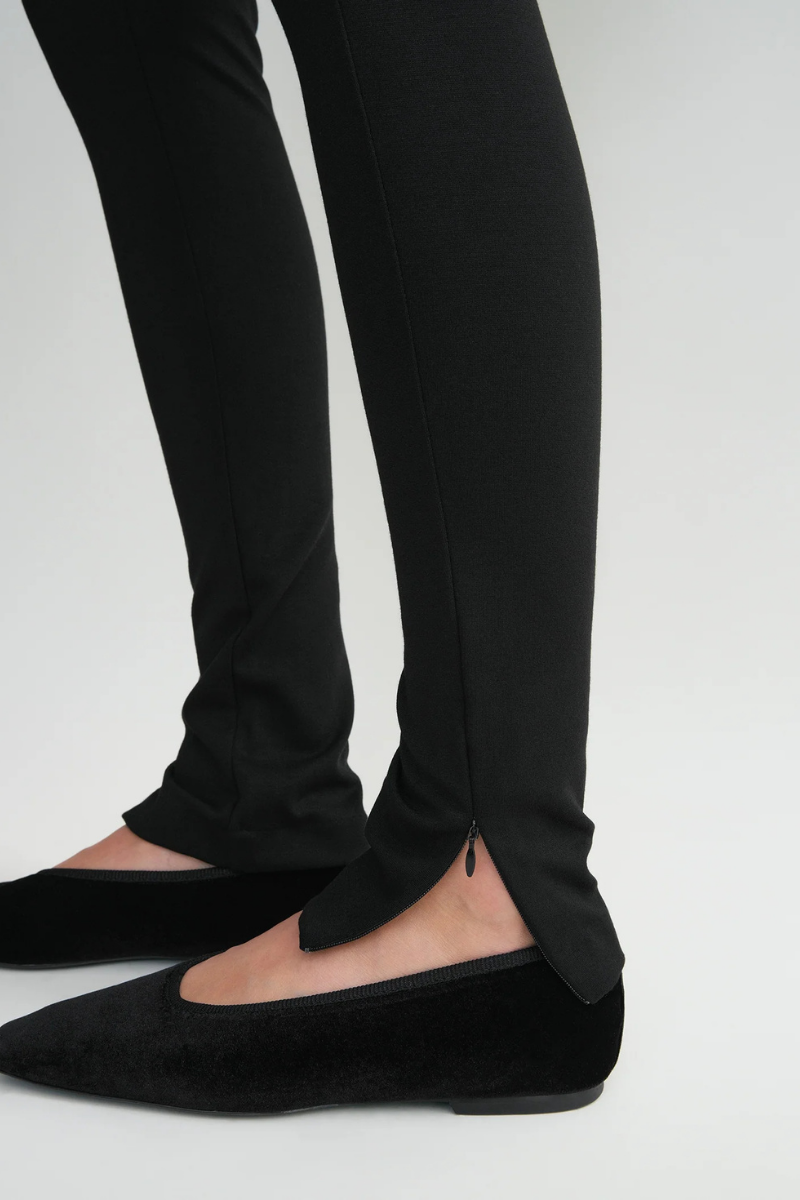 Toteme Zip Leggings in Black with zip detail paired with stylish black flats.