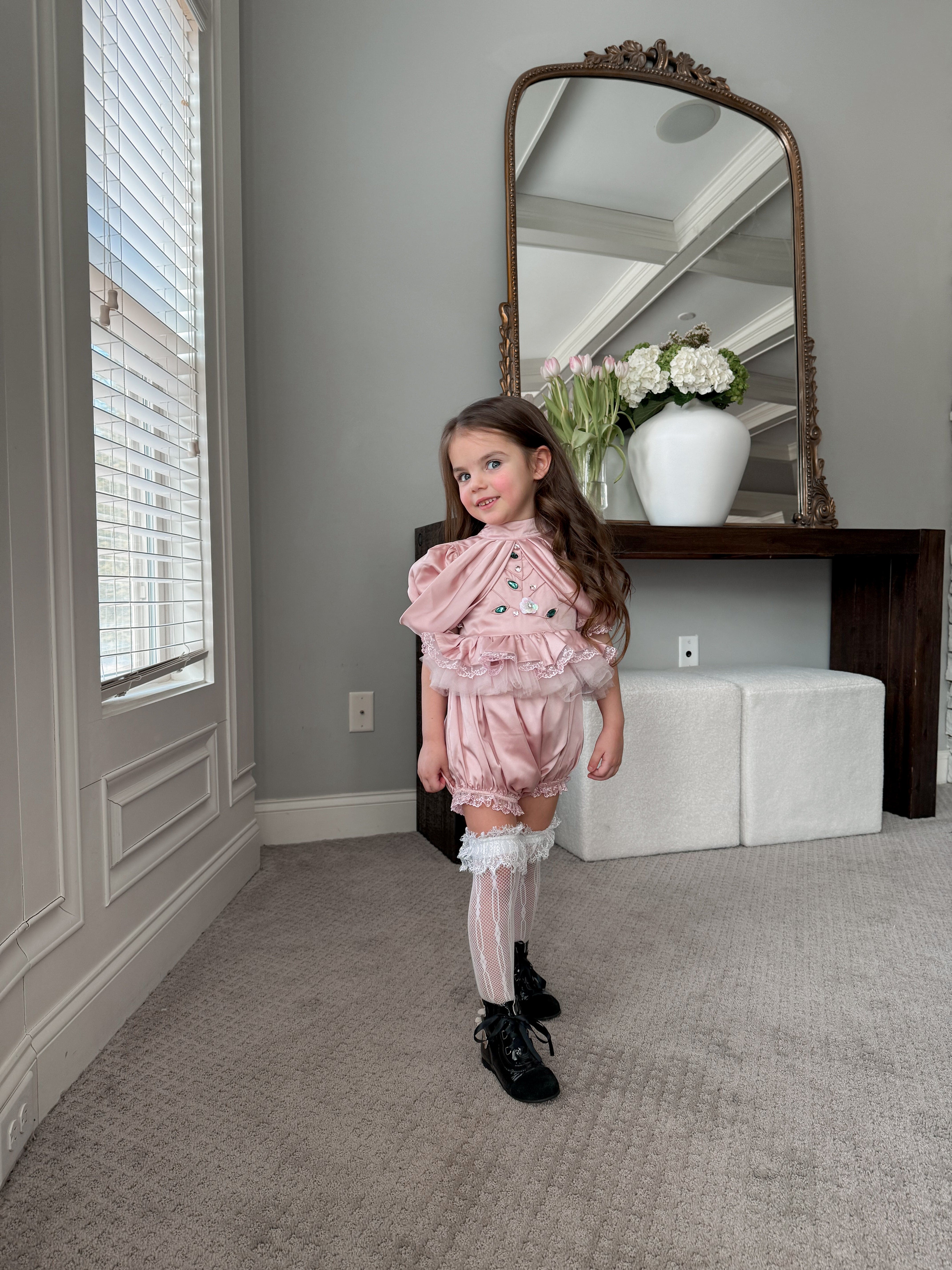 Girls blush pink satin romper with ruffled bodice, lace trim, and gem embellishments