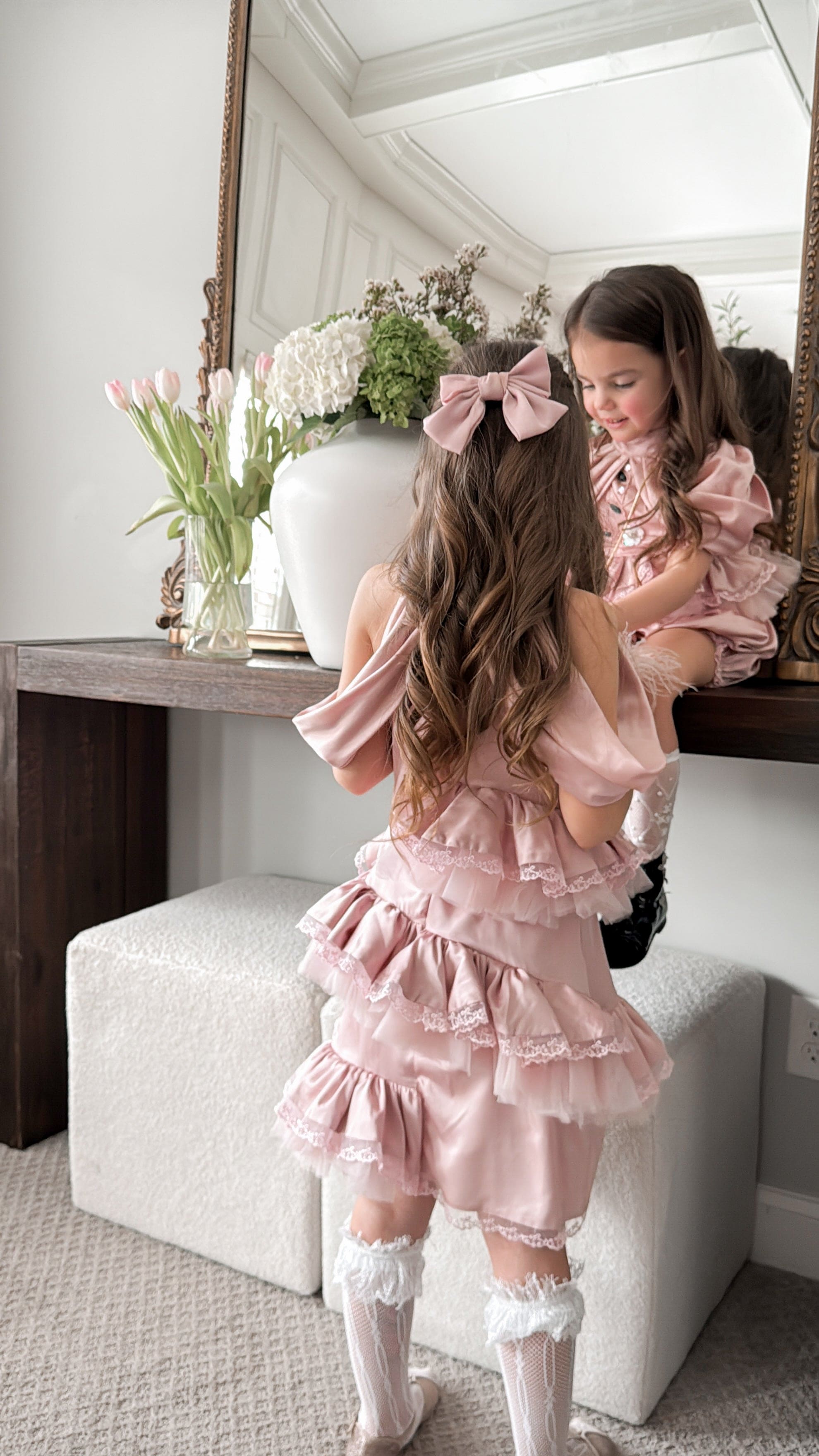Back view of pink satin ballerina dress with tiered lace trim skirt and off the shoulder satin drape 