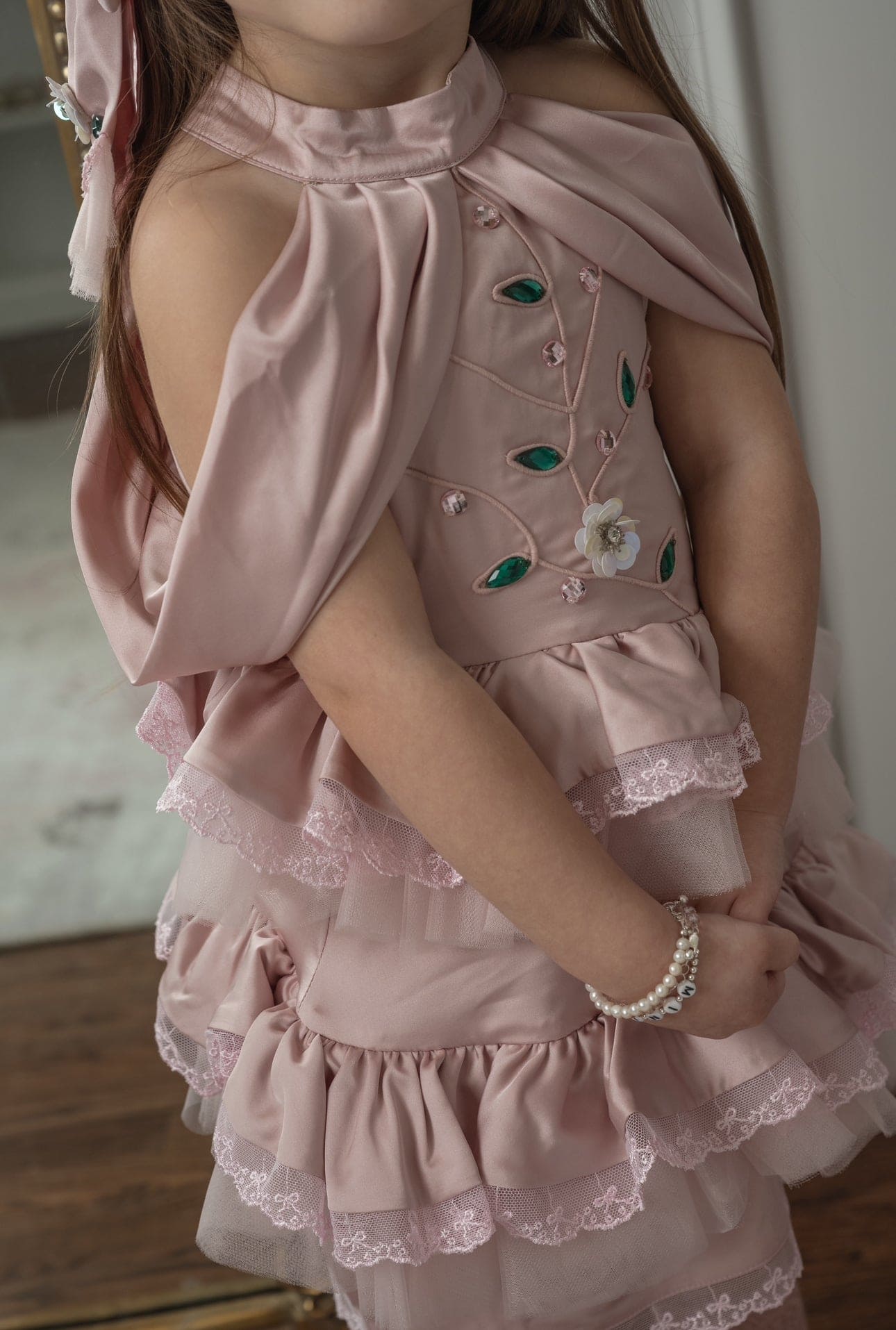 Detailed view of the pink satin ballerina dress showcasing pleated satin fabric, jewel embroidery, and ruffle trim