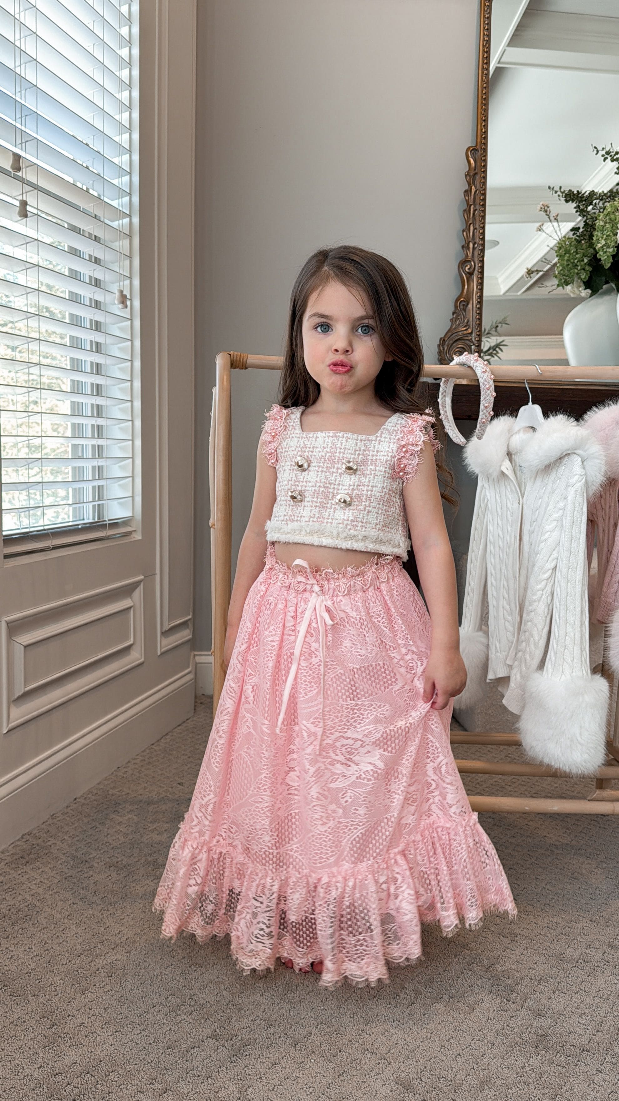 Girl wearing a beige and pink tweed top with a floral bracelet and pink lace skirt 