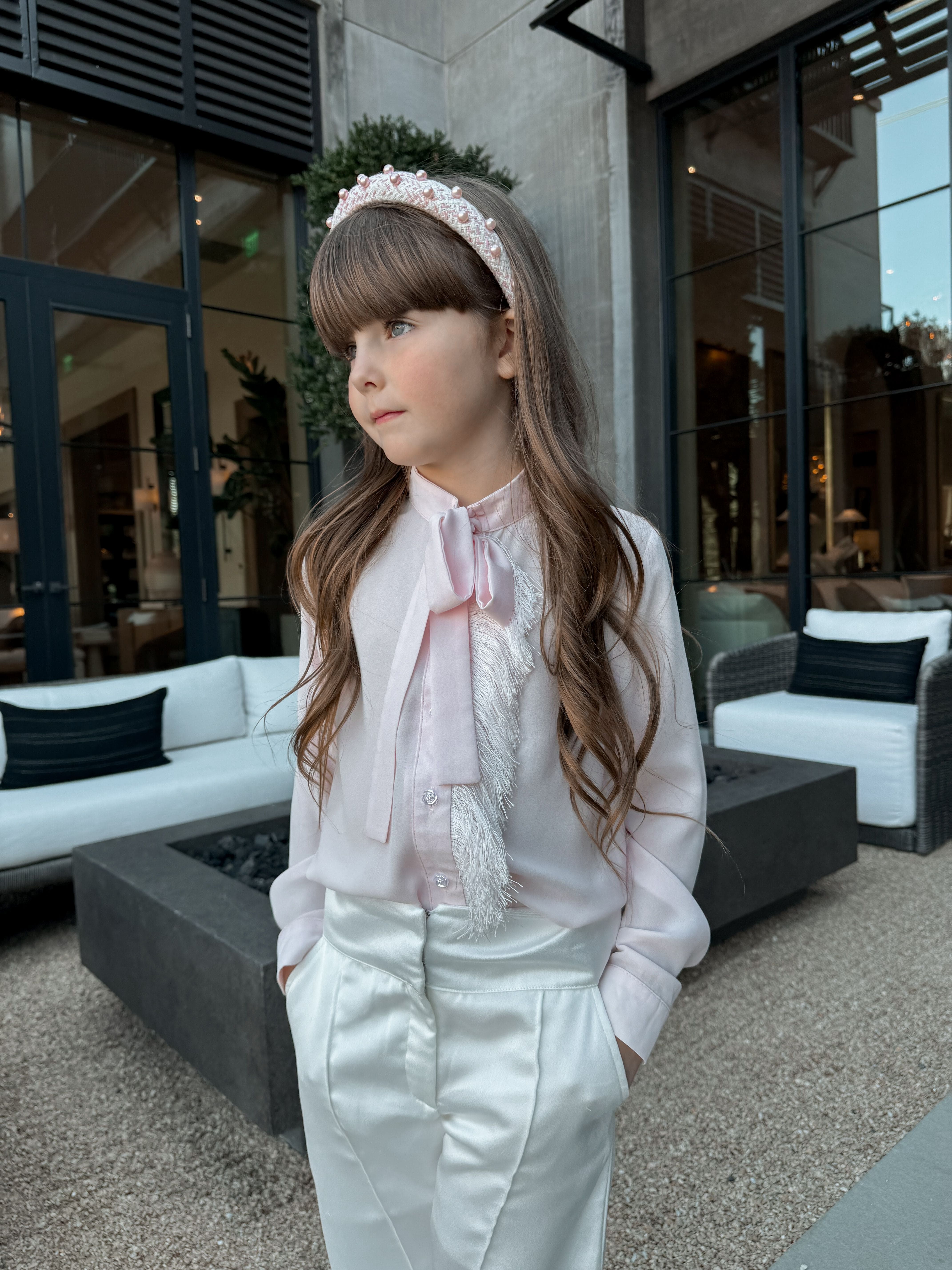 Blush pink girls outfit with bow blouse, white satin pants, and tweed headband