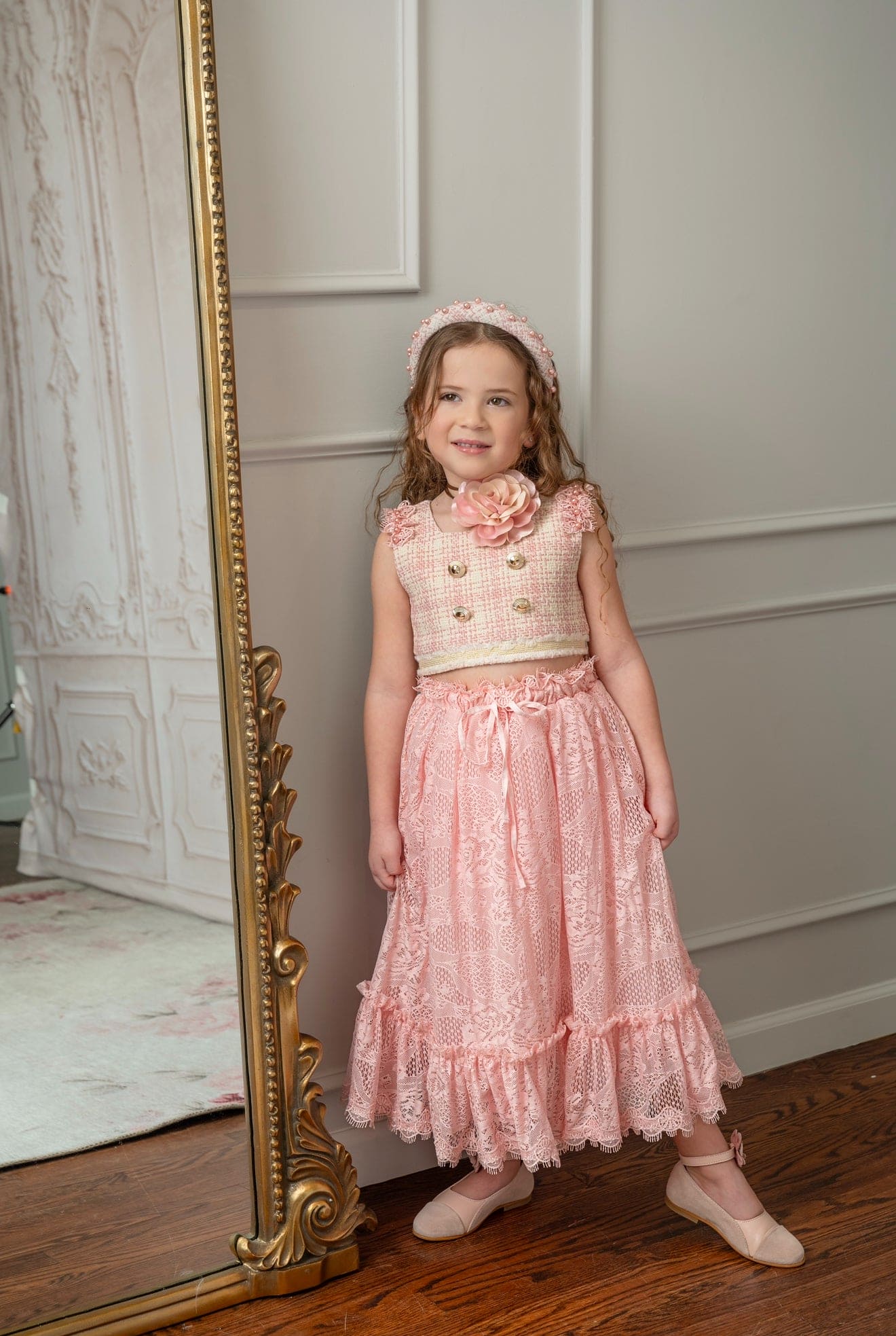 Girl wearing a beige and pink tweed top with a floral necklace and pink lace skirt 