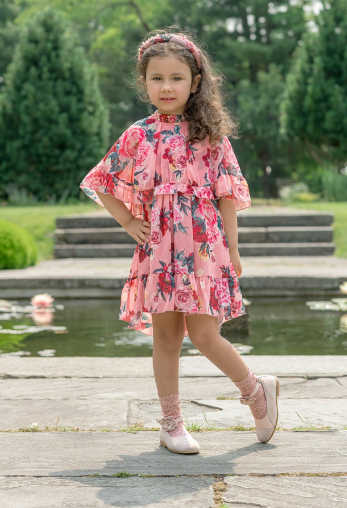 Girl wearing the Flora pink flower print dress outdoors, showcasing the flowy pattern on a blush pink base