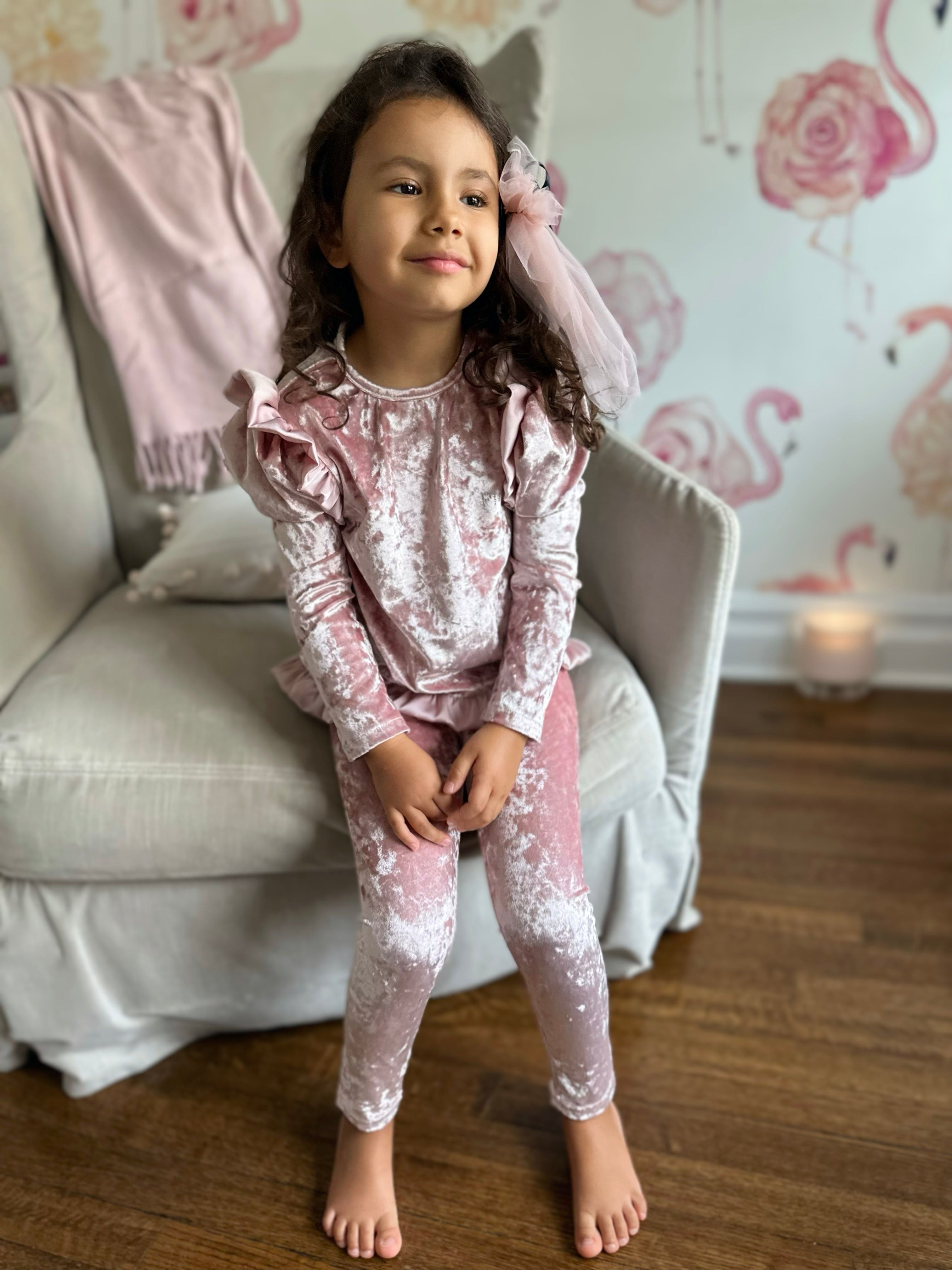 Little girl wearing pink velour lounge set with ruffle shoulder detail and matching leggings, cozy luxury girls lounge outfit