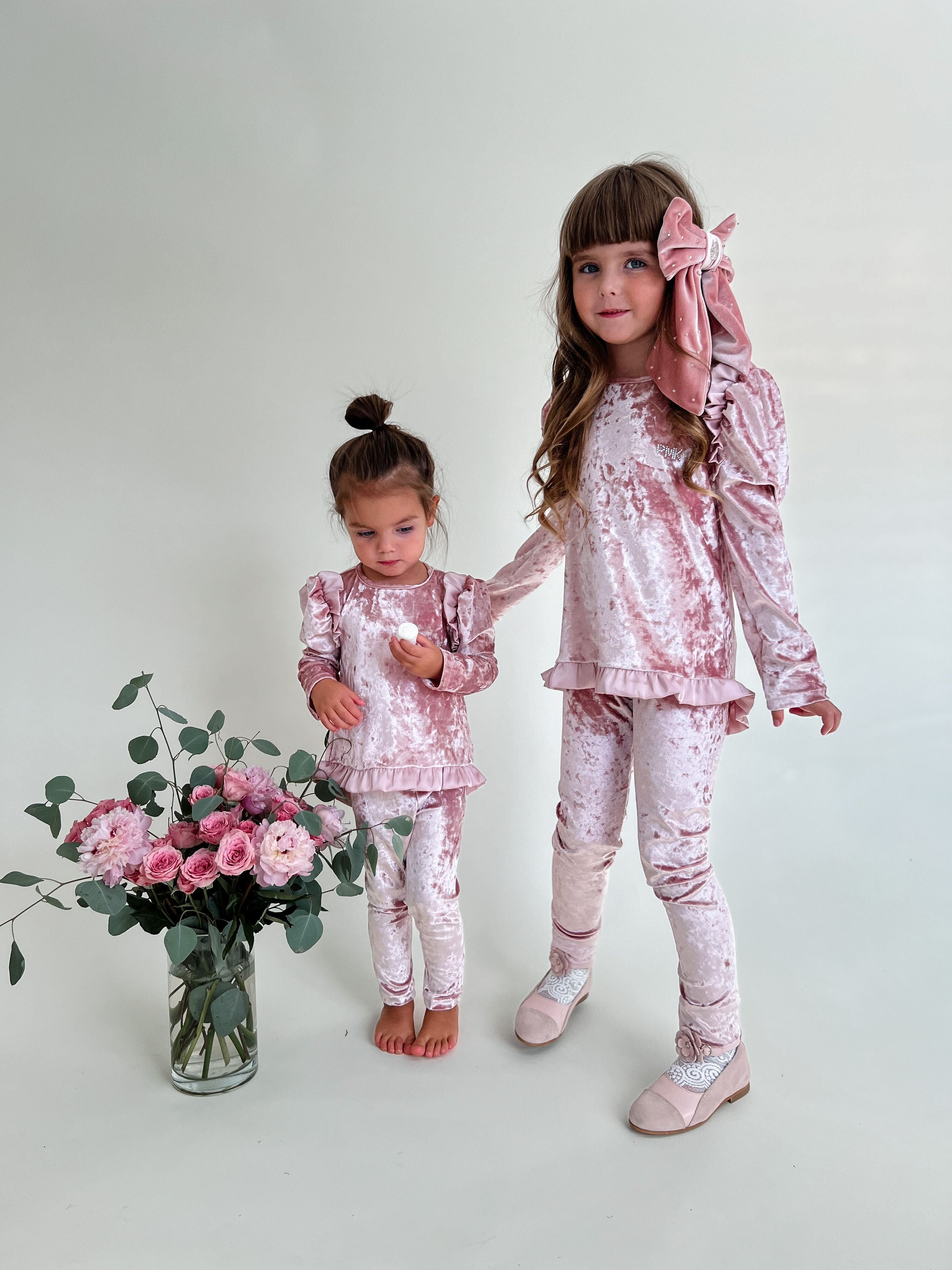 Girls styled in matching pink velour lounge sets with ruffle trim and fitted leggings, luxury sibling loungewear outfit