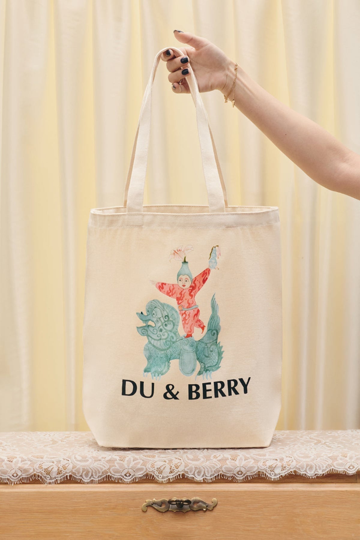 Du & Berry Cotton Tote Bag with artistic colorful illustration and long handles held by hand