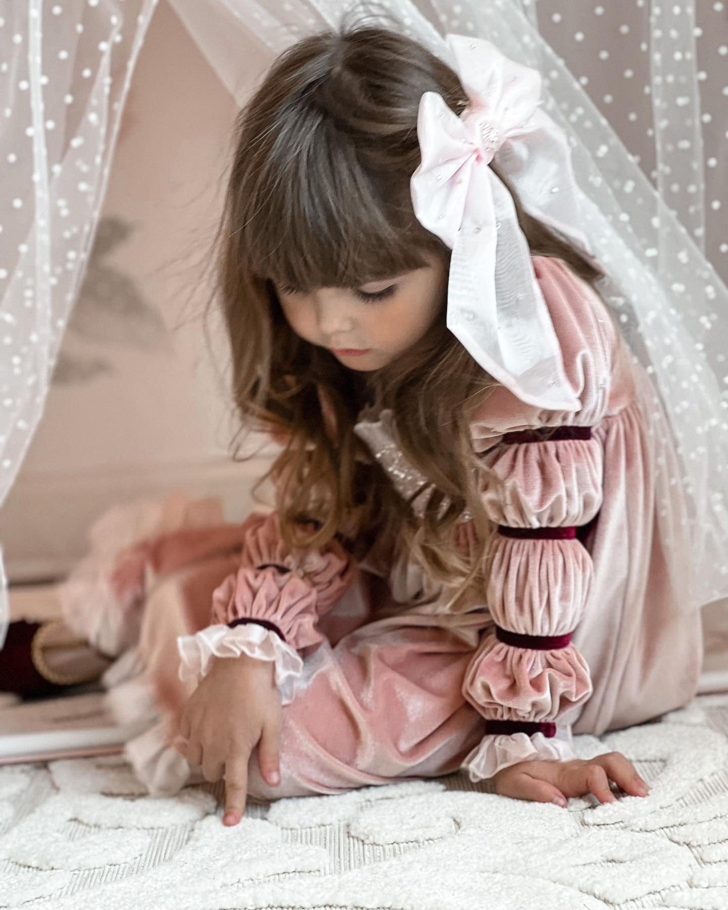 Little girl in blush velvet dress wearing Juliette Pink Organza Hair Bow with pearl-dotted sheer tails and elegant oversized silhouette.