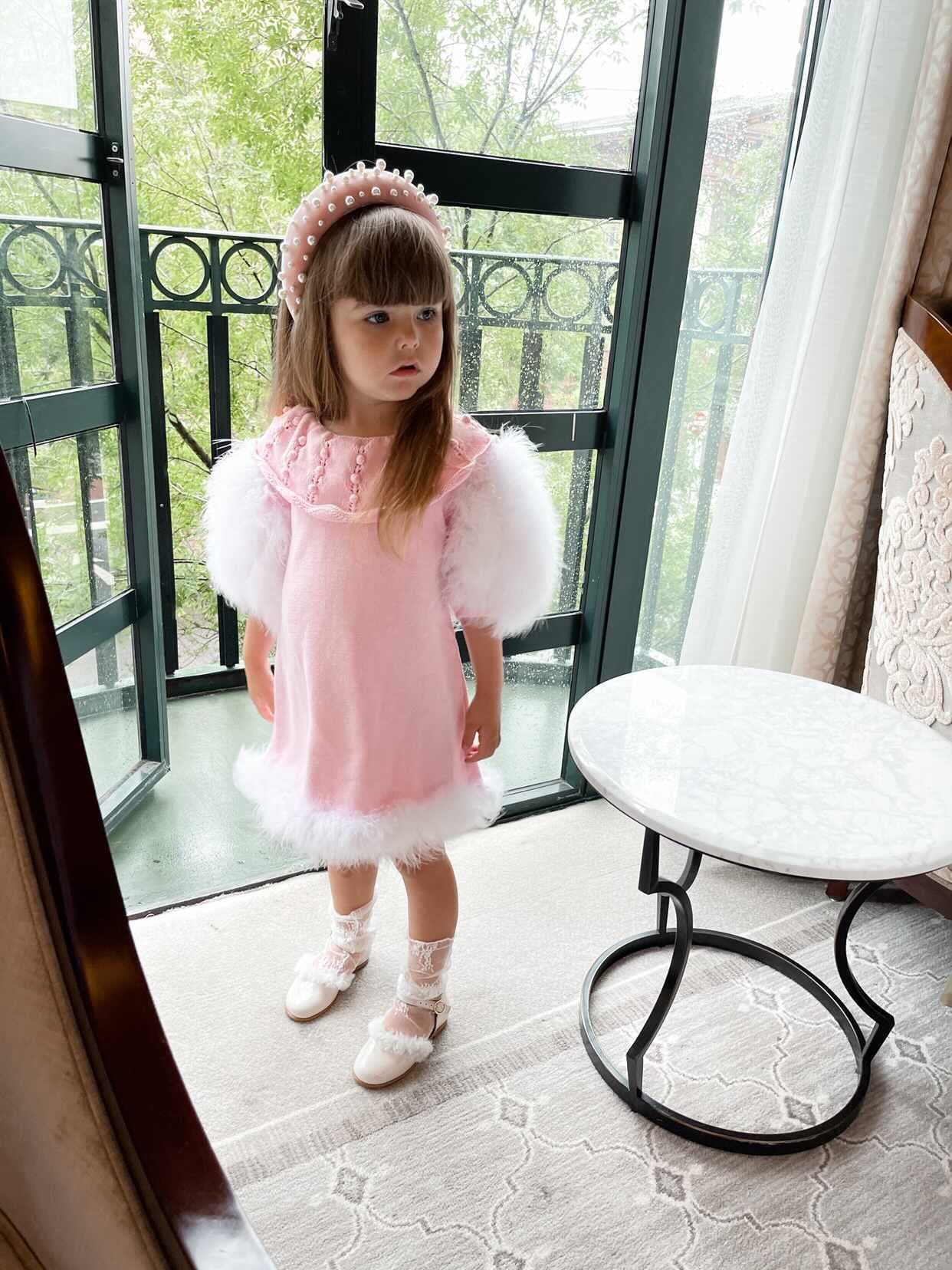 Young girl wearing Ella Knit Pink Feather Dress front angle with decorative collar and soft silhouette