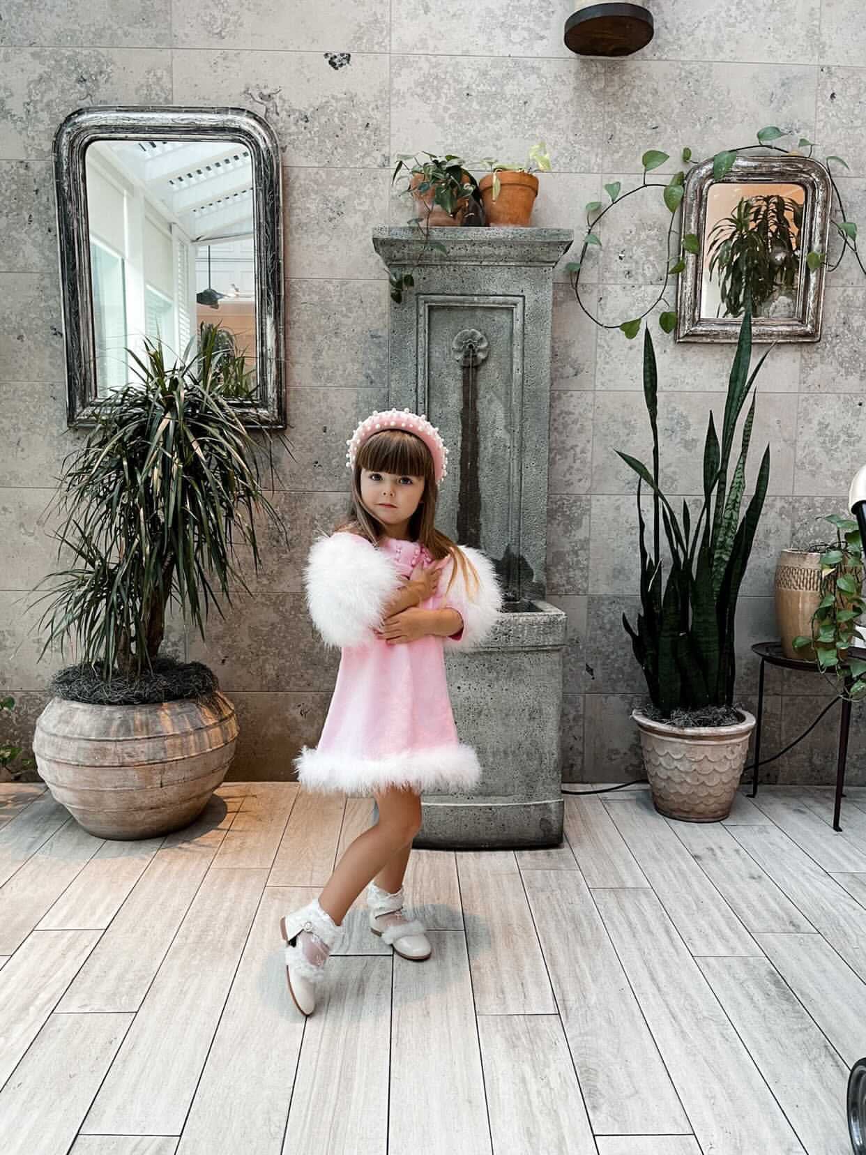 Little girl modeling Ella Knit Pink Feather Dress front view showing embellished collar and feather sleeves